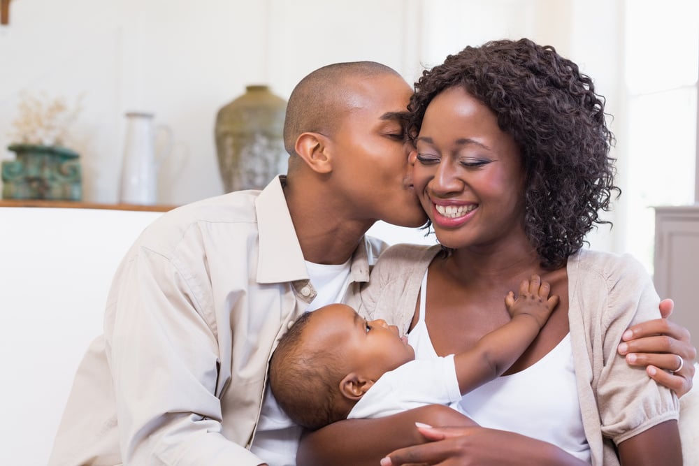 Happy parents spending time with baby on the couch at home in the living room